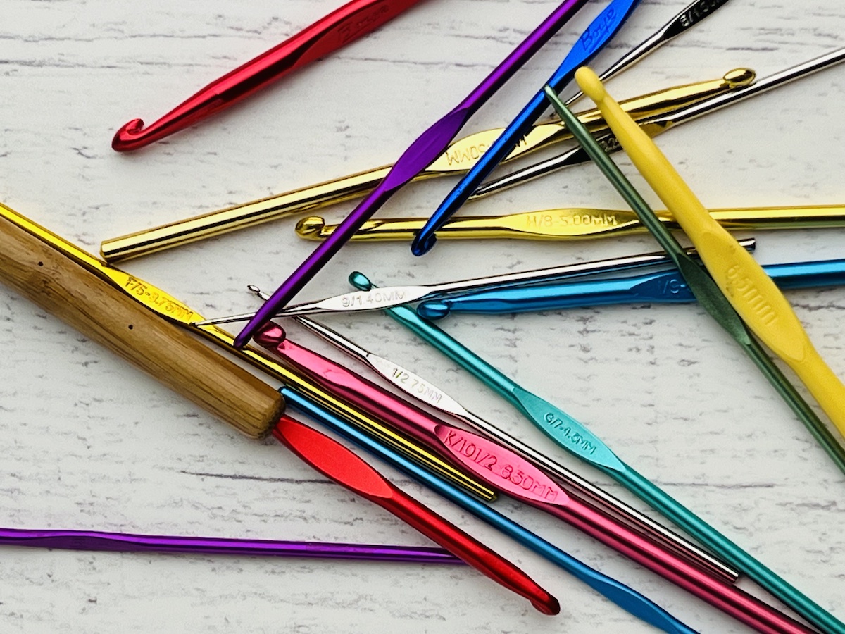 different sizes and colors of crochet hooks in a pile