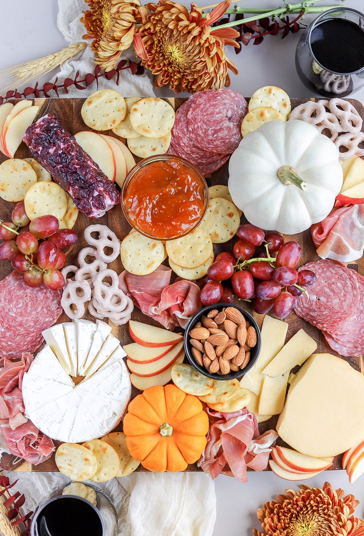 Cheeses, meats, pumpkin butter, grapes, almonds, and cinnamon yogurt pretzels are presented on Bits and Bites fall charcuterie board.