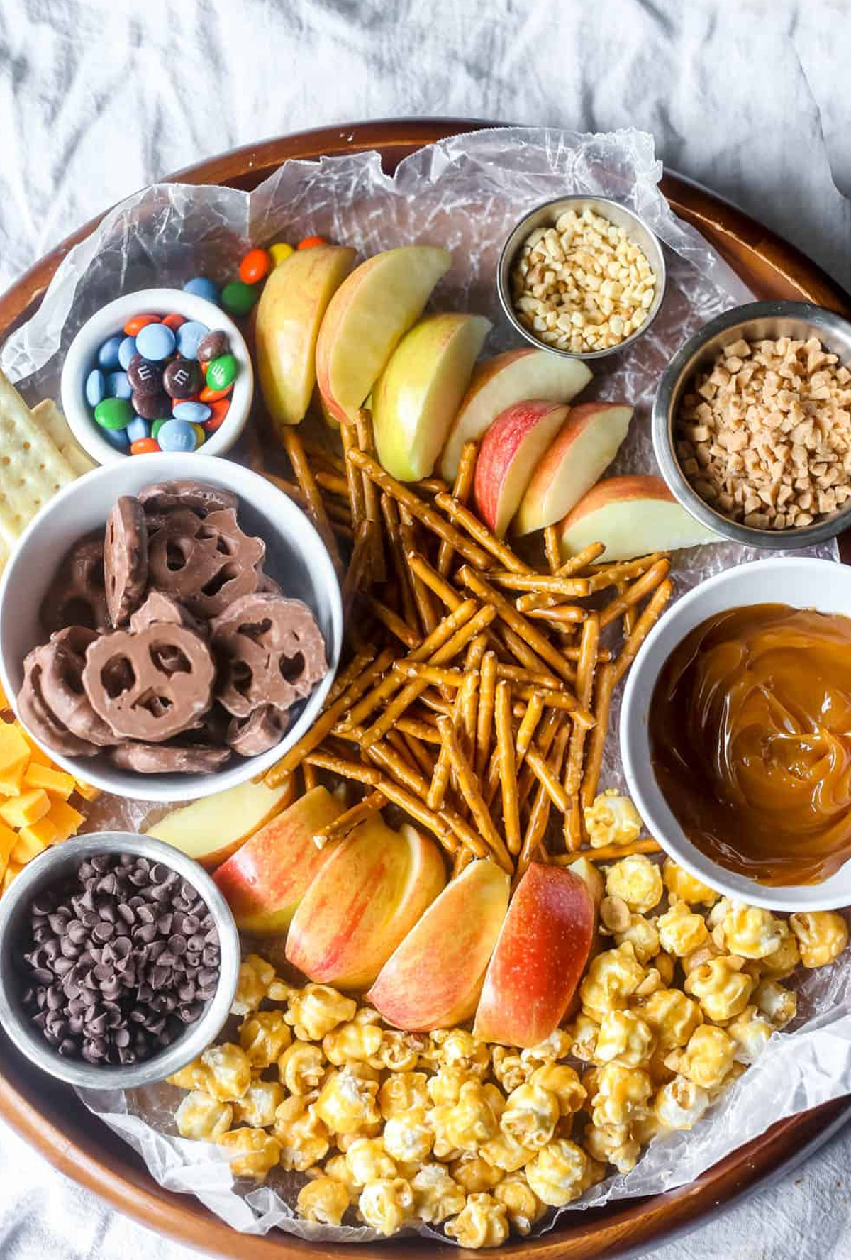 B Sugar Mama's fall charcuterie board includes apples, caramel dip, popcorn, pretzels, and chocolate covered pretzels.