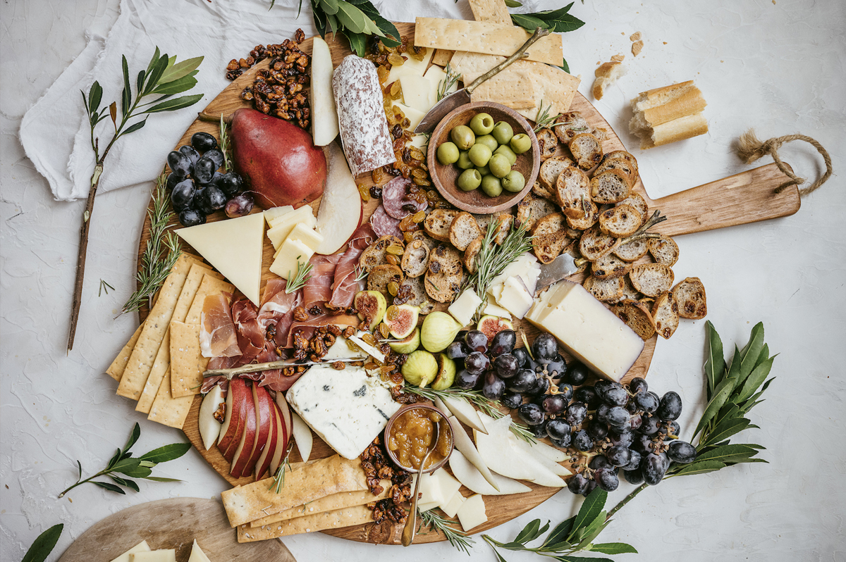 Camille Styles fall snack board showcases cheddar and blue cheese, meats, nuts, and fruit.