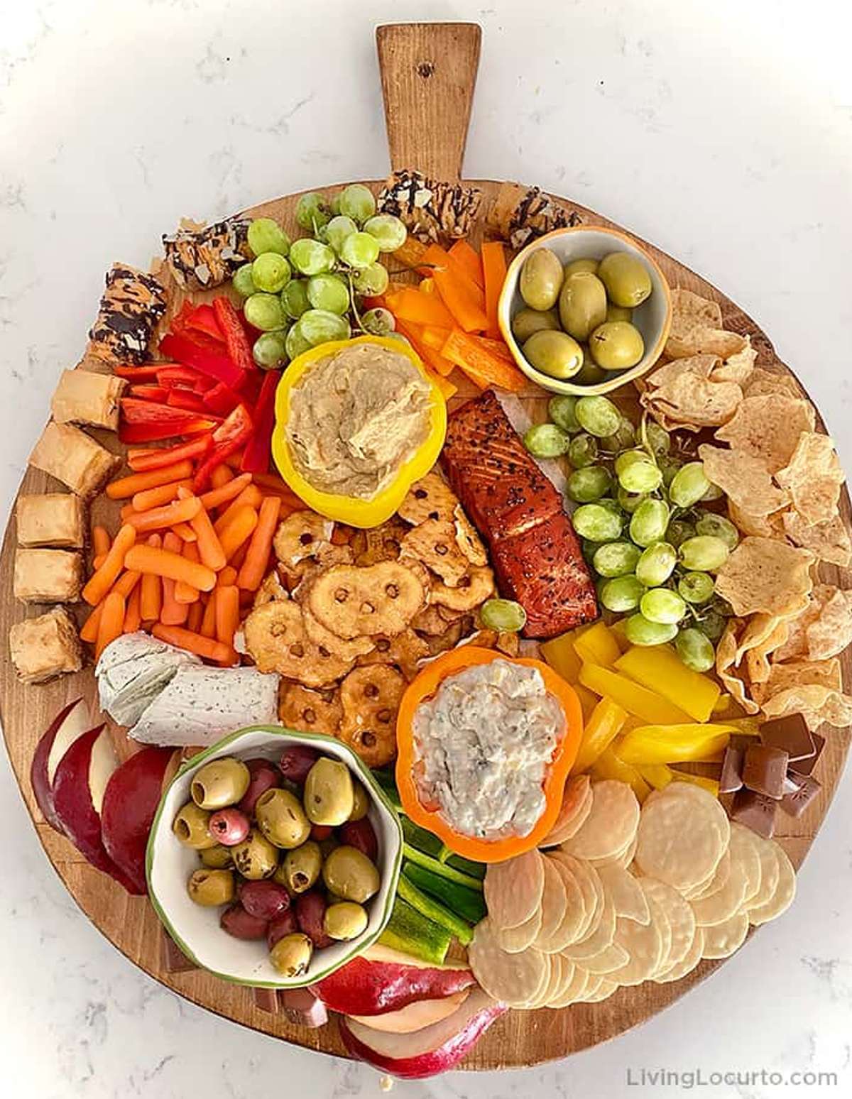 Hummus, bell peppers, olives, crackers, pretzels, and carrots fill Living Locurto's autumn themed charcuterie board.