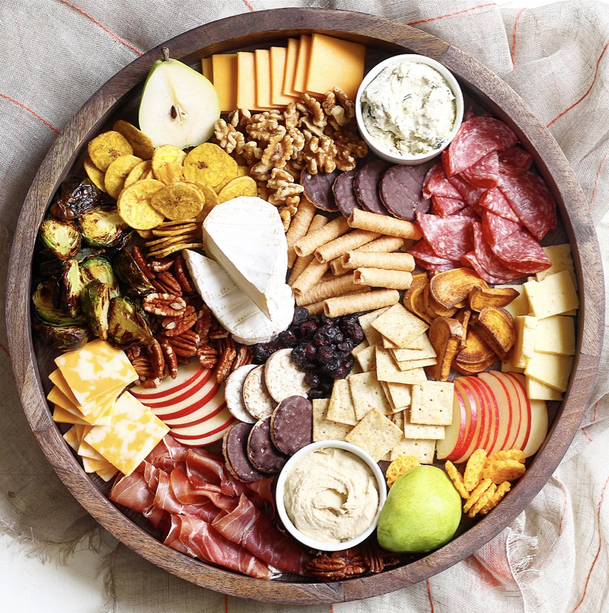 Milk and Honey Nutrition's fall charcuterie board has crackers, nuts, apples, meats, and cheeses.