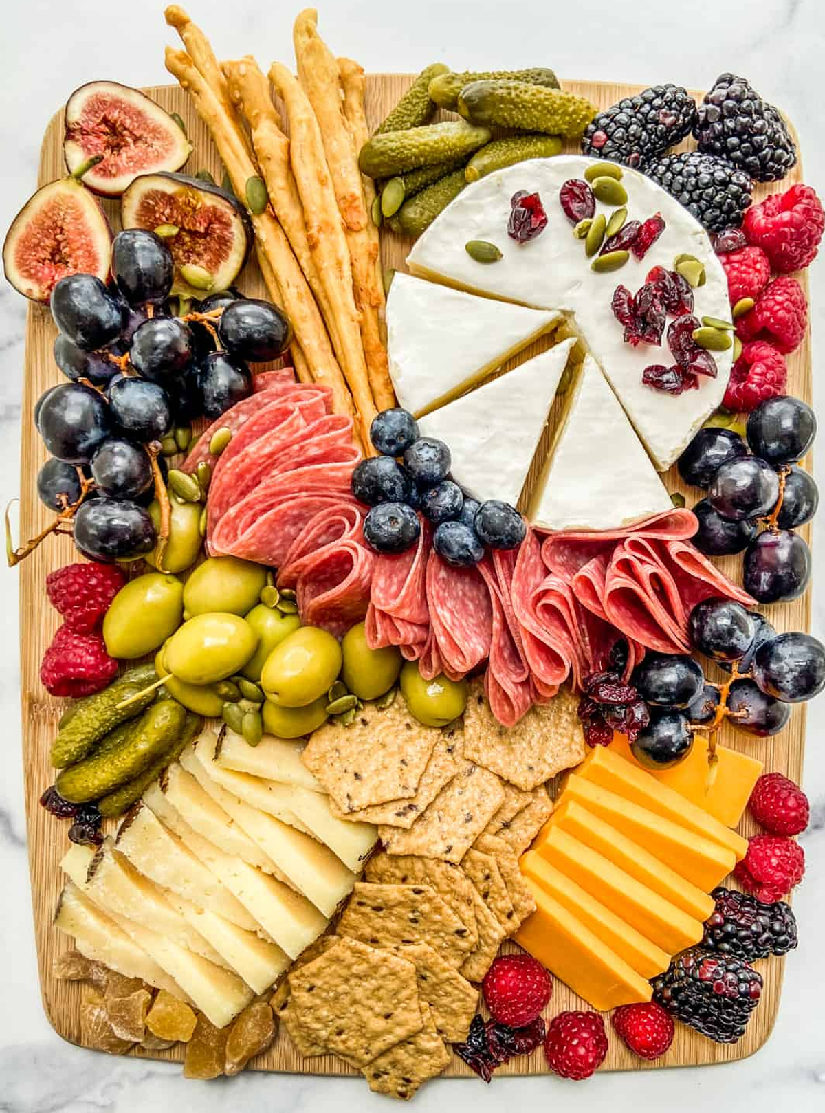 A beautiful display of cheese, berries, figs, grapes, and deli meat fill This Healthy Table's board.
