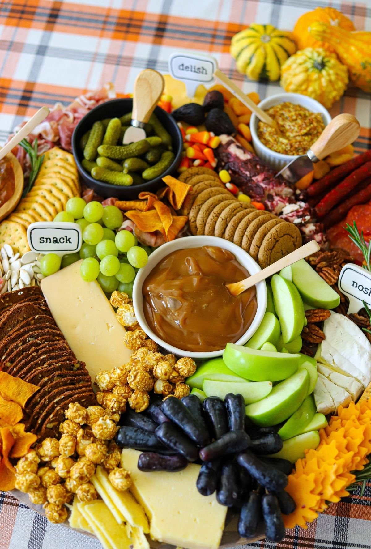 This Mom's Menu's autumn themed board displays cheese, apples, creamy caramel, crackers, and popcorn.