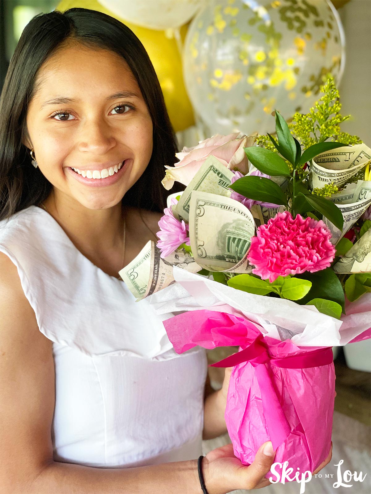 girl holding money bouquet with a pink flower, and a balloon