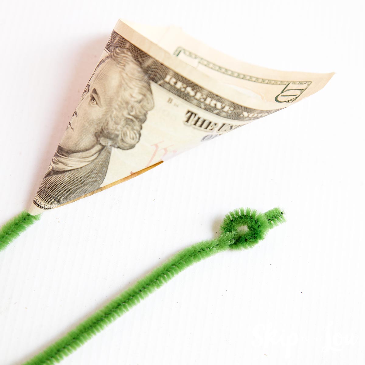 bill shaped into a cone placed on pipe cleaner to make money flower