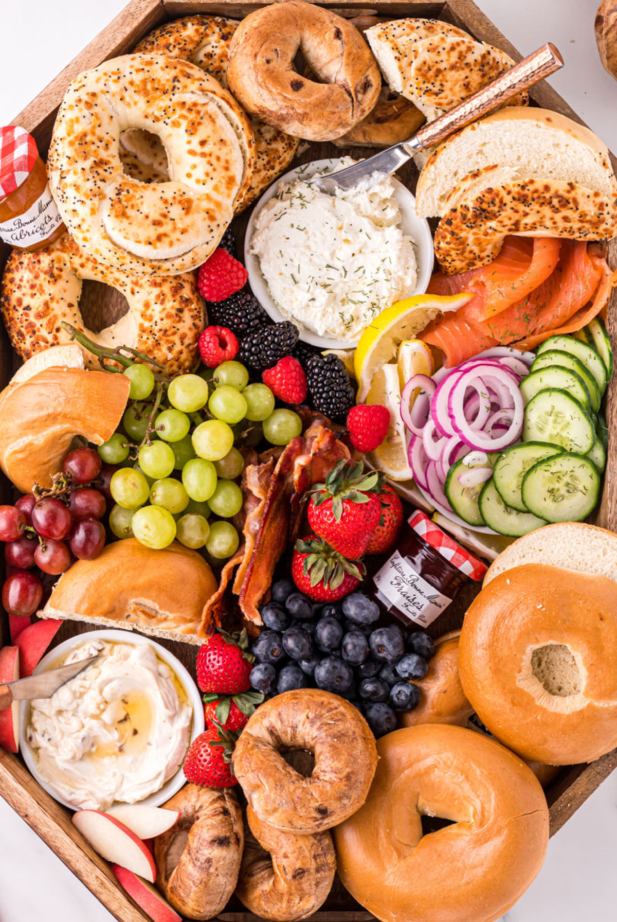 a full board of bagels, fruit, veggies, and cream cheese from bread booze bacon. 