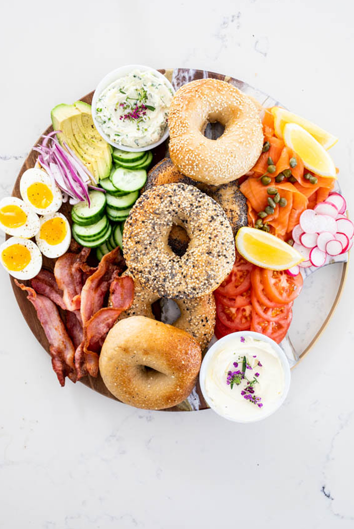 simply delicious food created a board with a variety of bagels, toppings, and cream cheese spreads.