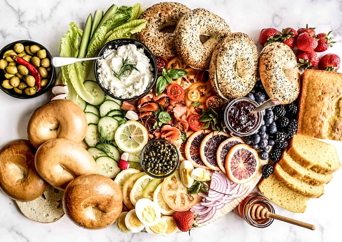 windy city dinner fairy created a board full of bagels, jams, fruits, and sweet breads.