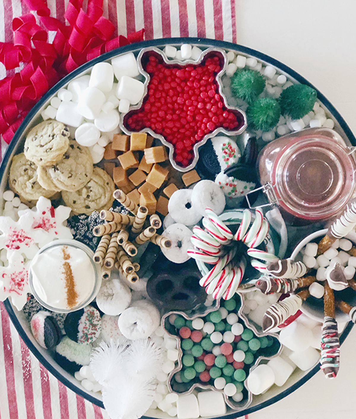 a holiday cocoa charcuterie board idea with a variety of choices like chocolate dipped pretzels, red hots, chocolate chip cookies, and more from heinen's.