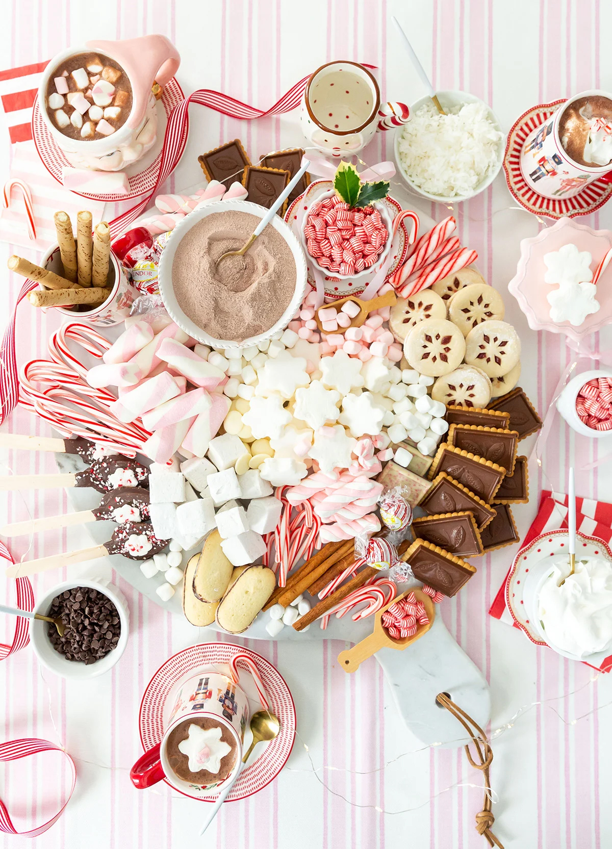 a pink and red themed cocoa board from pizzazzerie with peppermints, pink marshmallows, and cookies. 
