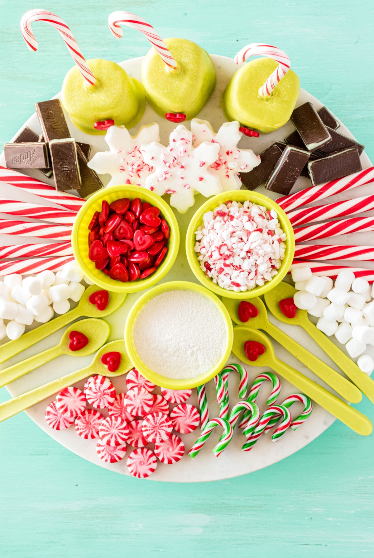 grinch themed cocoa board with red heart candies, snowflake cookies, andes mints, and green chocolate dipped marshmallows from simplistically living.
