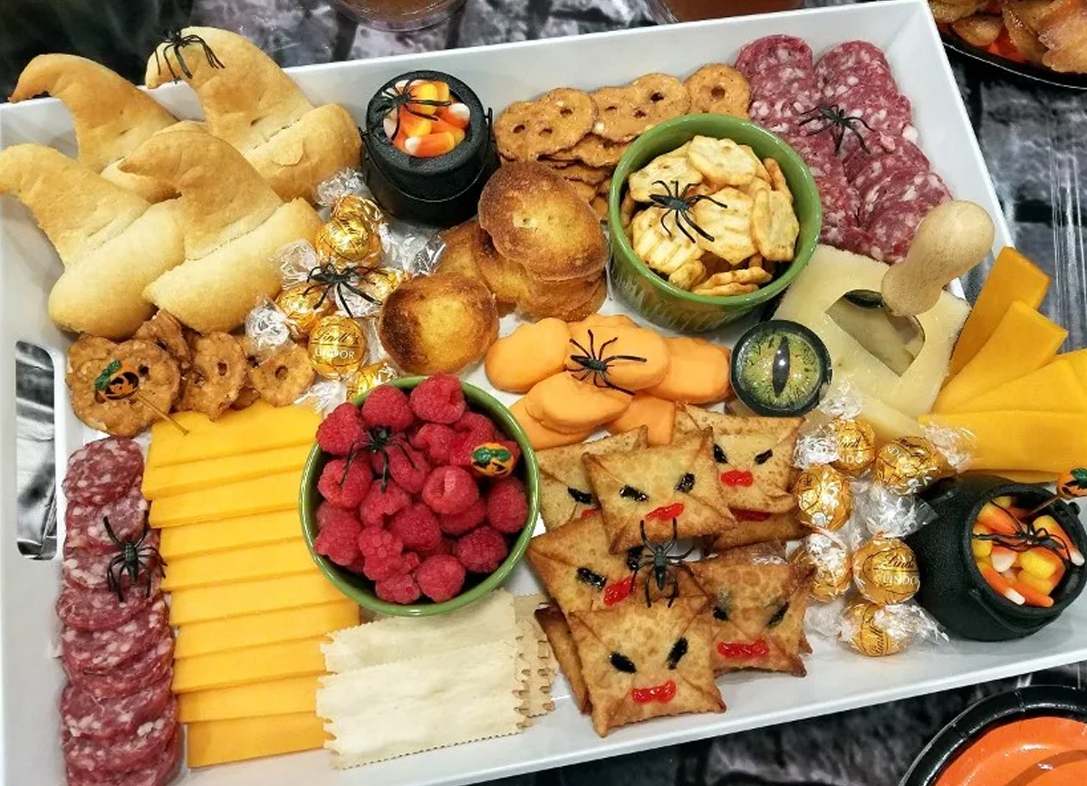 The Scrap Shoppe Blog created a Harry Potter charcuterie board that includes meat, cheese, raspberries, crackers, and candy corn.