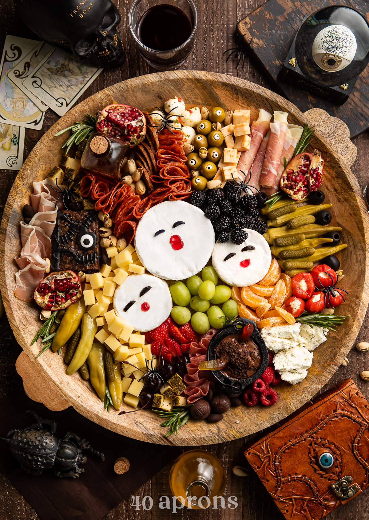 40 Aprons board is filled with olives, meats, cheeses, and fruit.