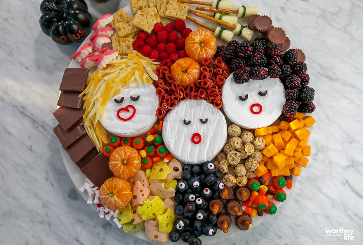 A Worthey Read's charcuterie board is filled with berries, candy pumpkins, clementine's, candy, meats, and cheese.