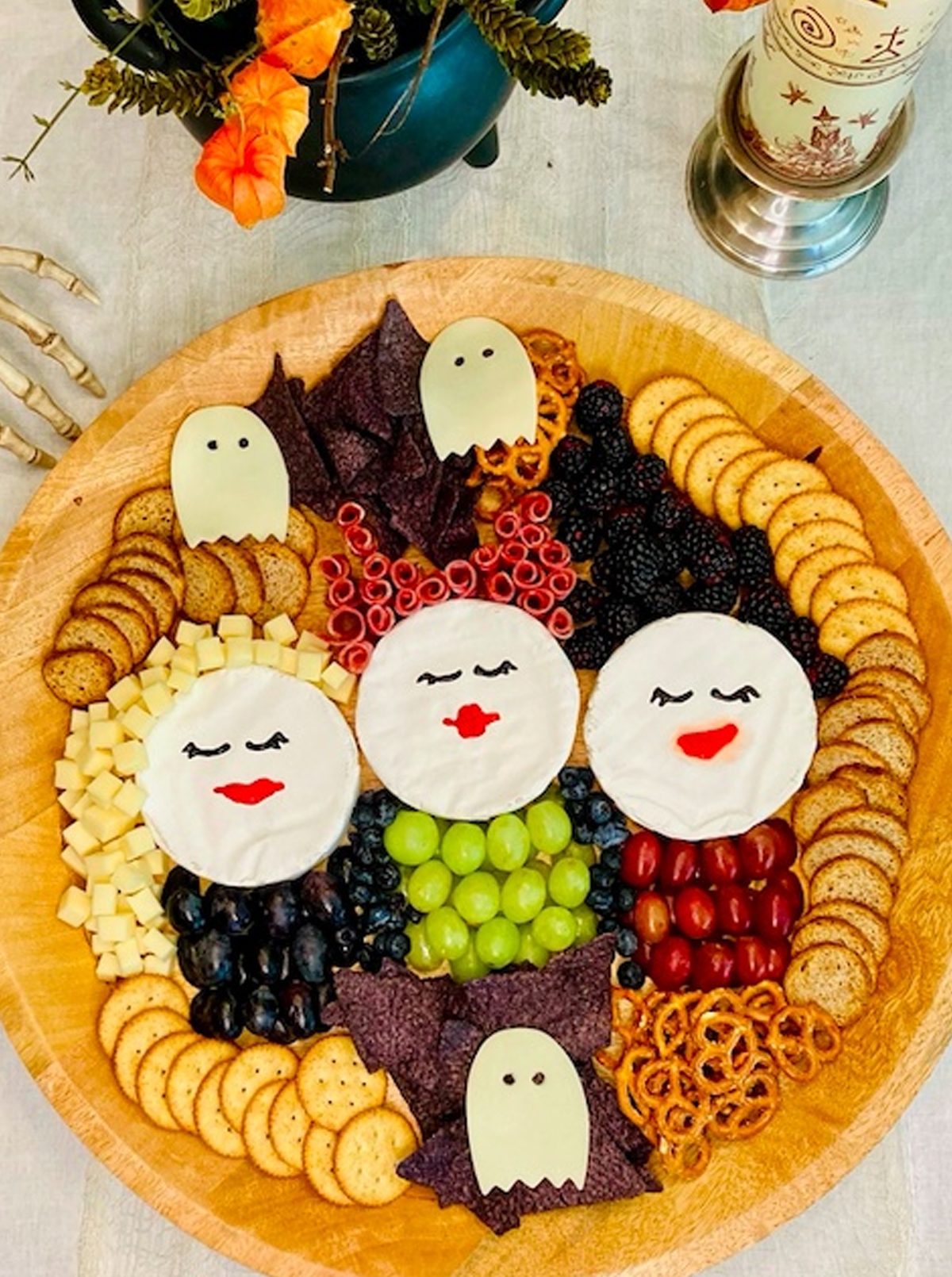 Pixie Dust & Posies board displays crackers, chips, berries, meats. cheese, and grapes.
