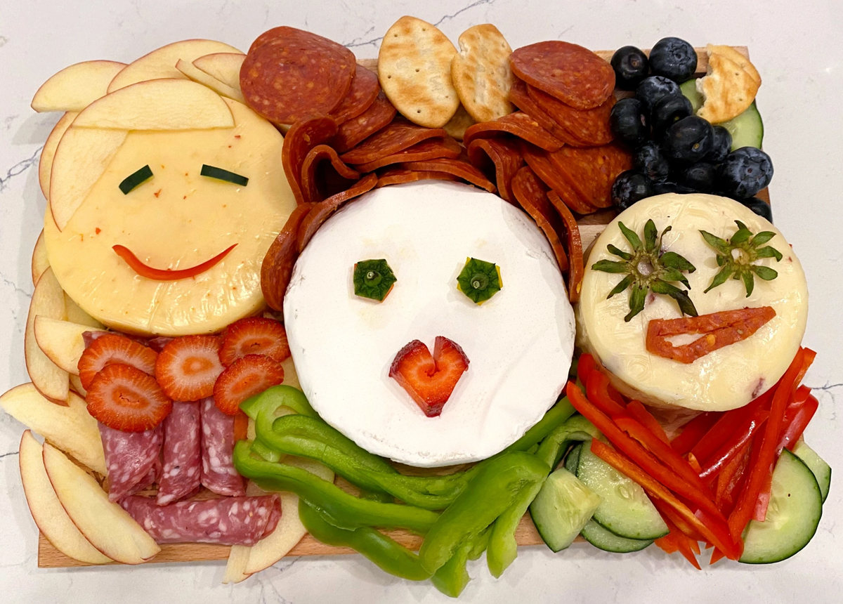 Wishes and Wayfindings board is full of cheese, peppers, cucumbers, blueberries, and meats.