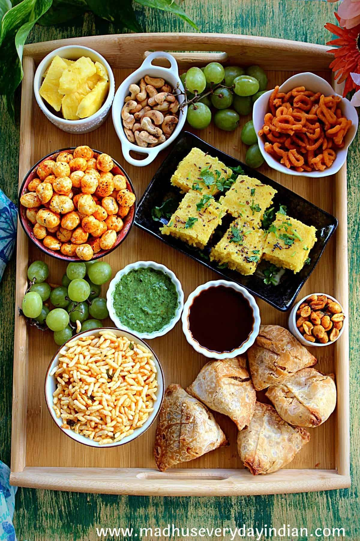 Samosa, vada, pani puri, chaats, and bonda is displayed on Madhu's Everyday Indian snack board.