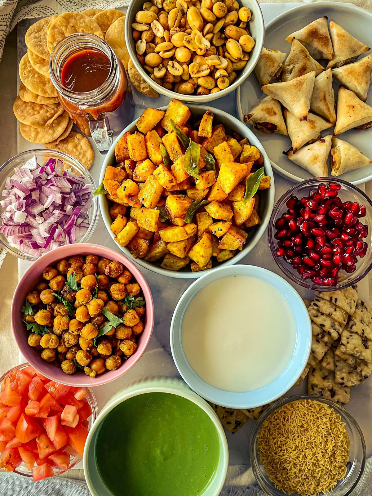 Sweet Simple Masala's charcuterie board presents spiced nuts, crispy poori, flaxseed crisps, and date chutney.