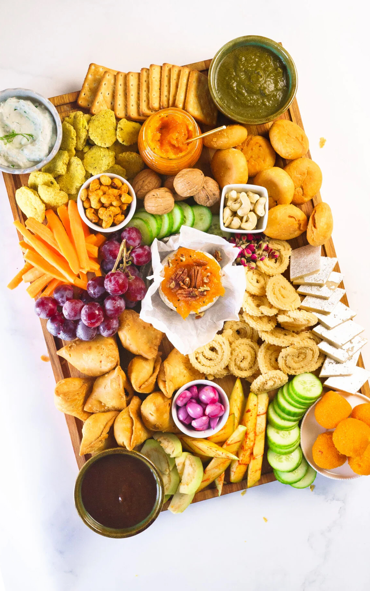 Samosas, tikki, kebabs, Hung Yogurt Dip, Baked brie, and mango jam are displayed on Yellow Thyme's snack board.