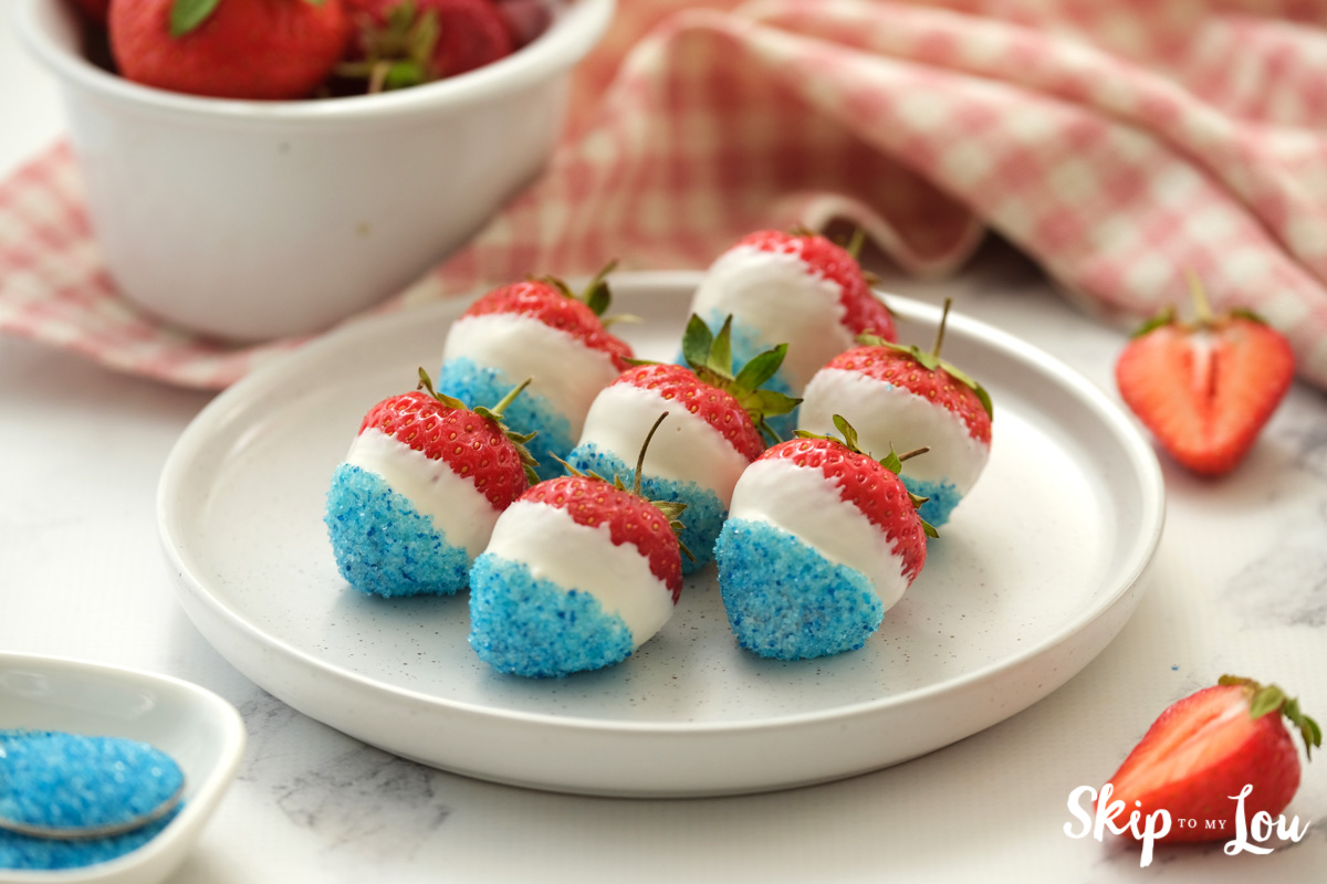 red white and blue strawberries on a white plate on top of a white table.