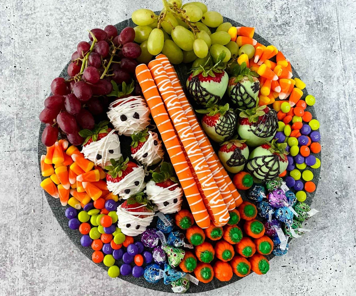 Brooklyn Active Mama's Halloween board showcases candy, chocolate-dipped strawberries, and grapes.
