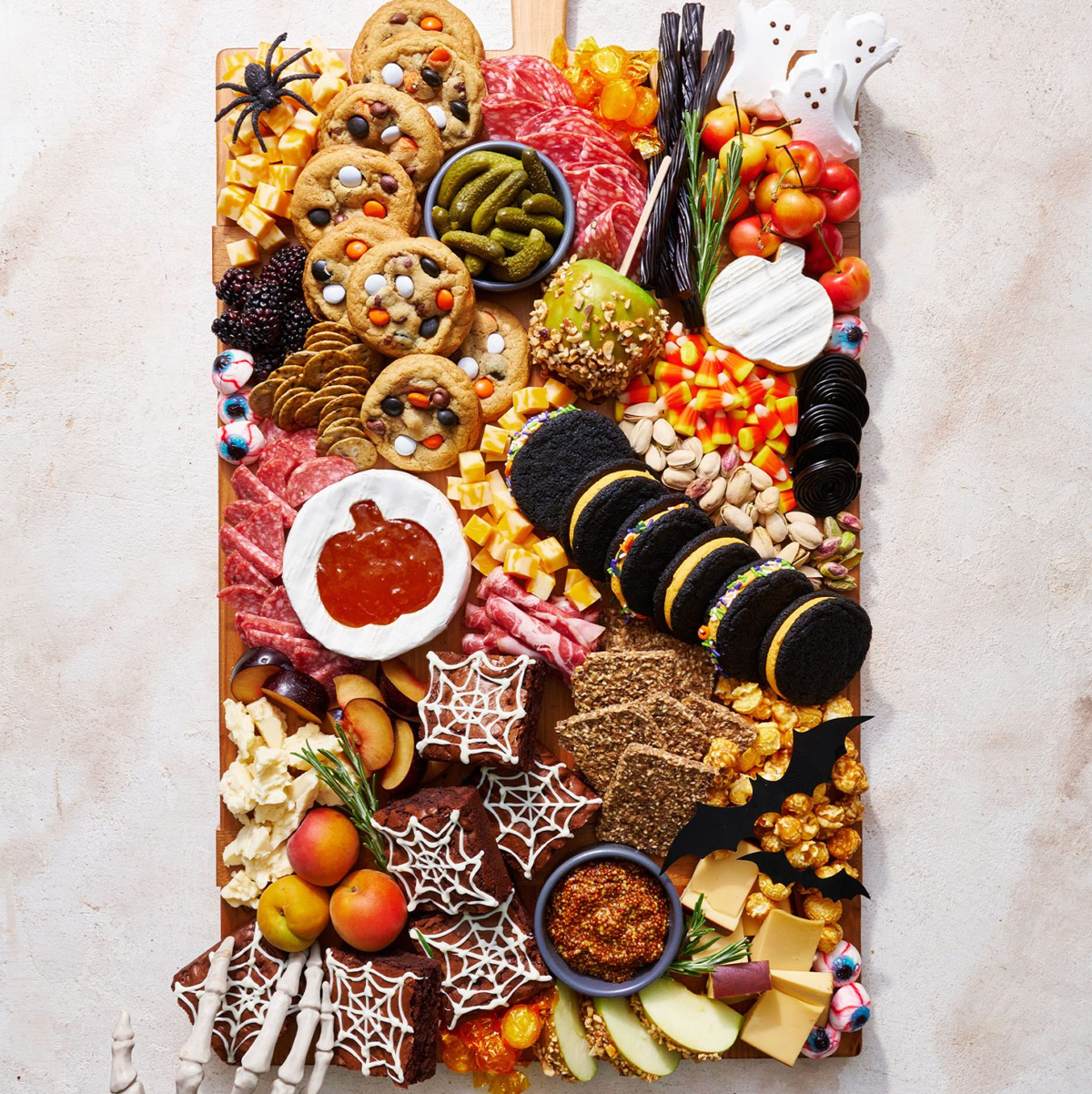 Cookies, candies, caramel dipped apple slices, cheese, and meat fill Handle the Heat Halloween board.