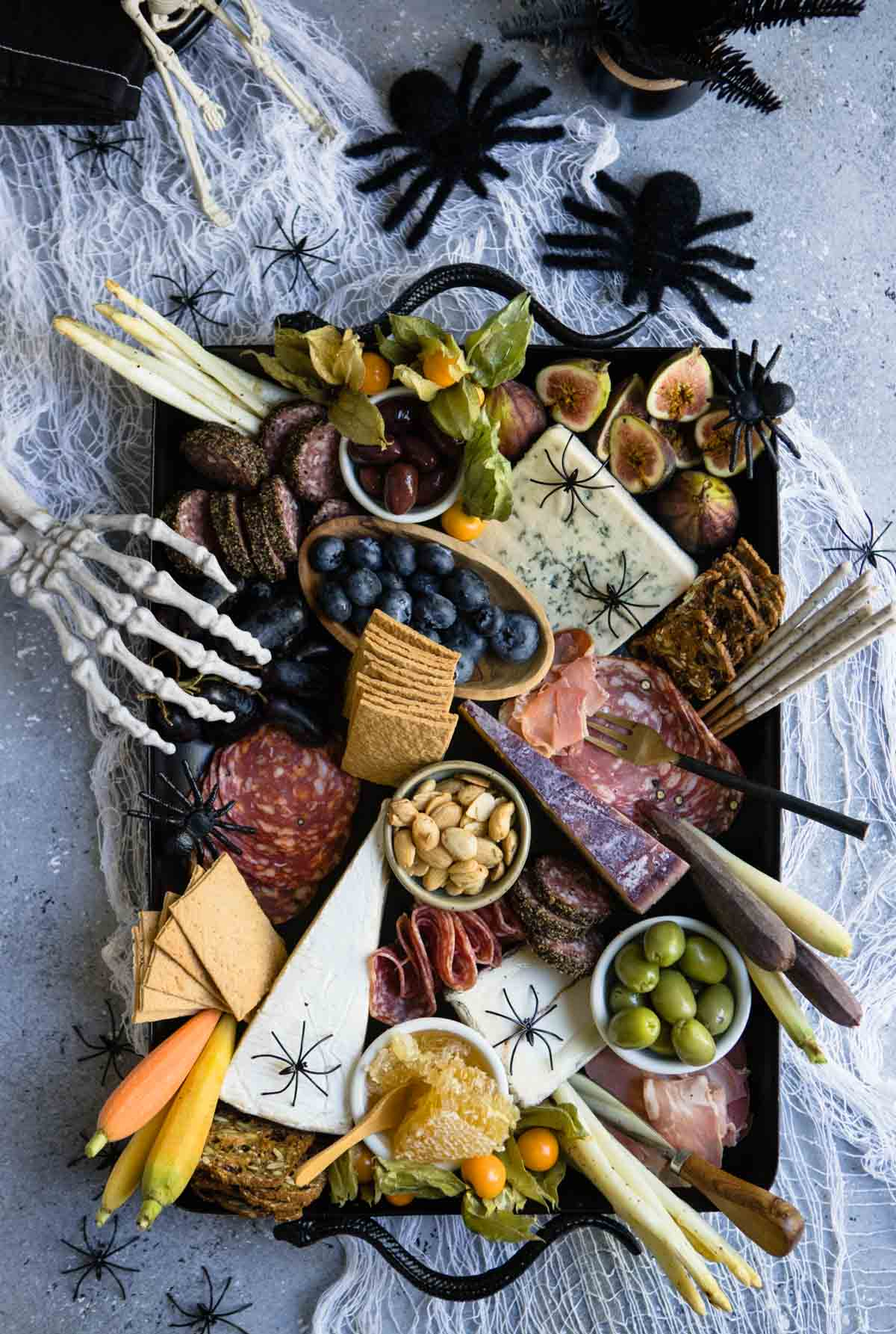 Fruit, crackers, meat, and cheese fill Howe We Live Halloween board.