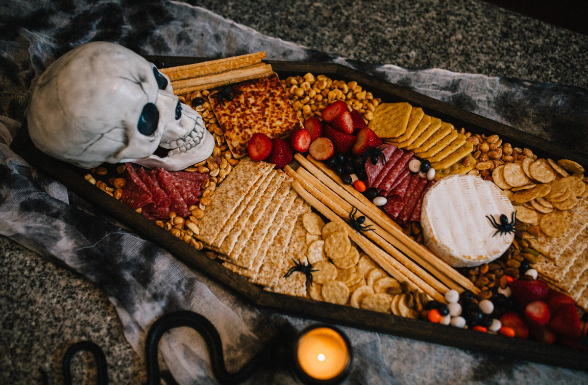 Ice Cream and Neon Dreams Halloween Coffin charcuterie board is filled with meats, cheese, crackers, and fruit.