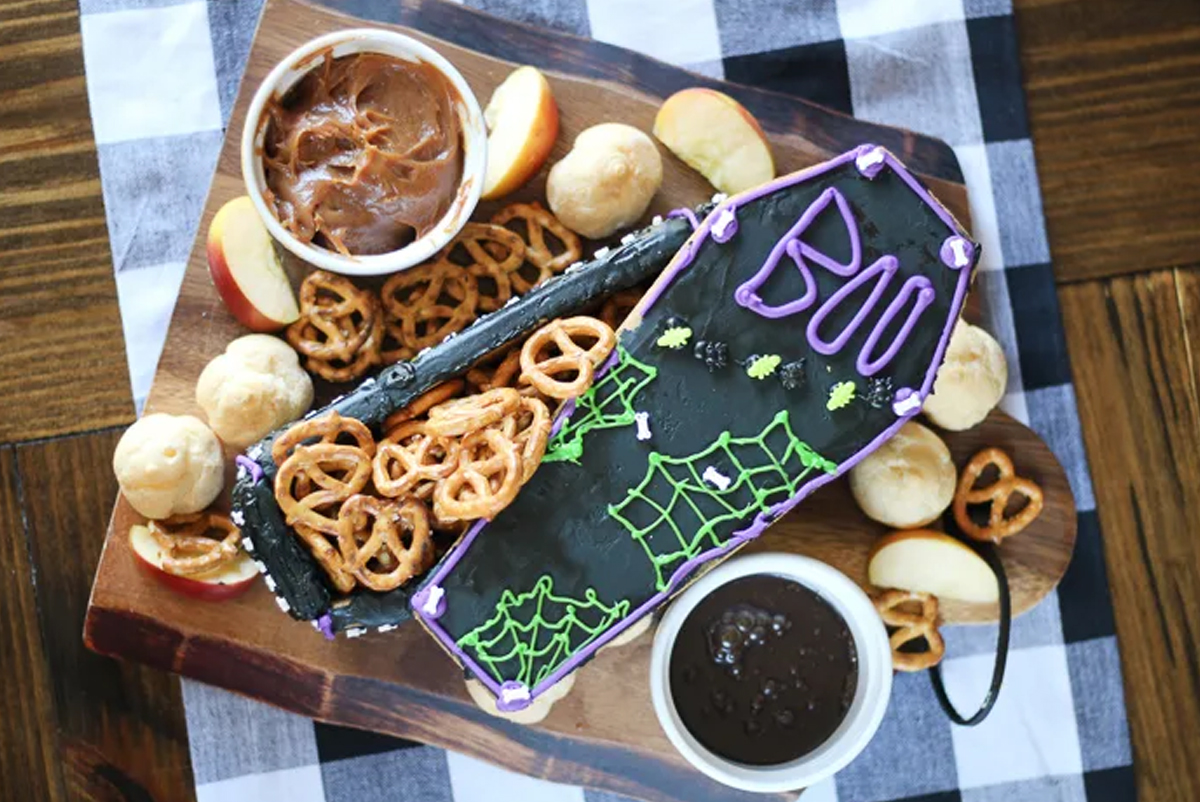 Apples, pretzels, and fondue fill Jen Around the World's Halloween Coffin Board.