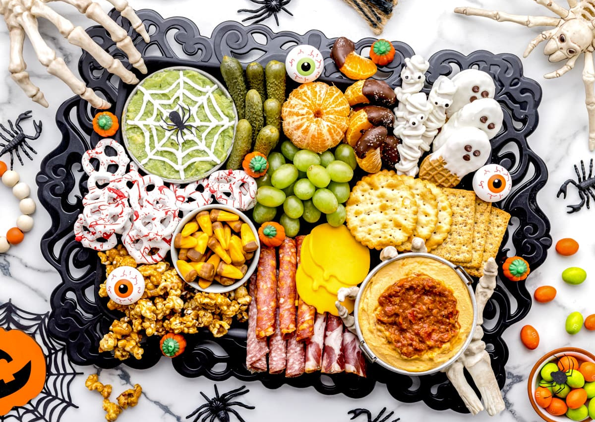 Lil Luna's Halloween Board includes guacamole, candy, cookies, fruit, meats, and cheese.