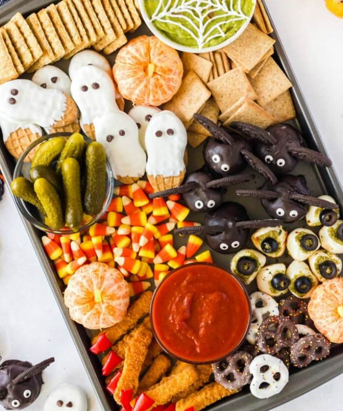 Oreos, pickles, cookies, crackers, and clementine pumpkins are presented on Mama Loves Food Halloween board.