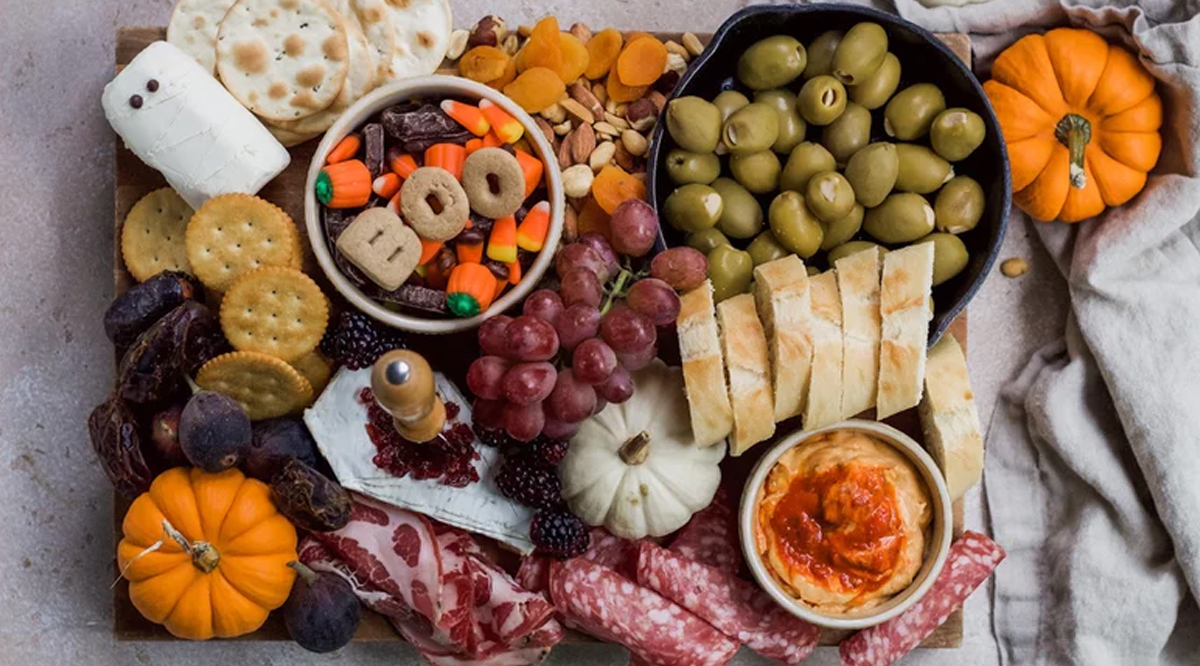 Mashed Halloween board is filled with olives, bread, cheese, crackers, and meats.