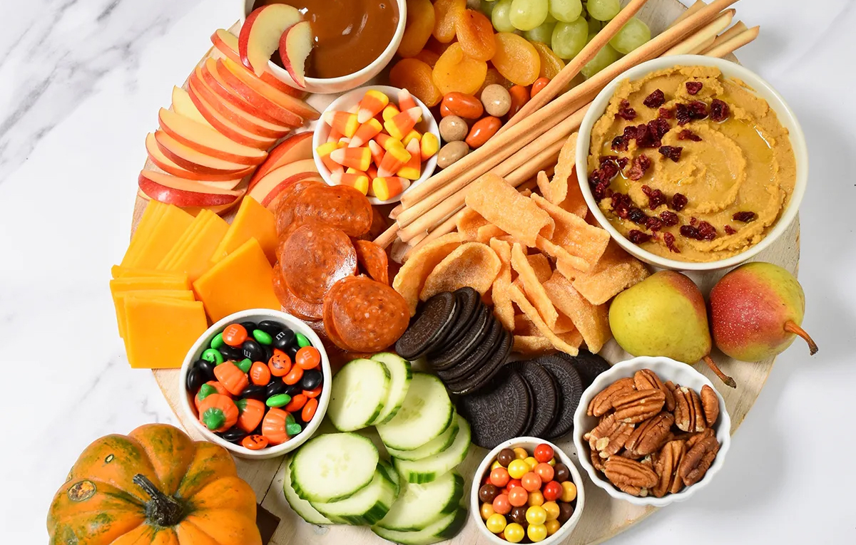 Hummus, cookies, nuts, cucumbers, and candy fill a Parade Magazine's Halloween Charcuterie board.