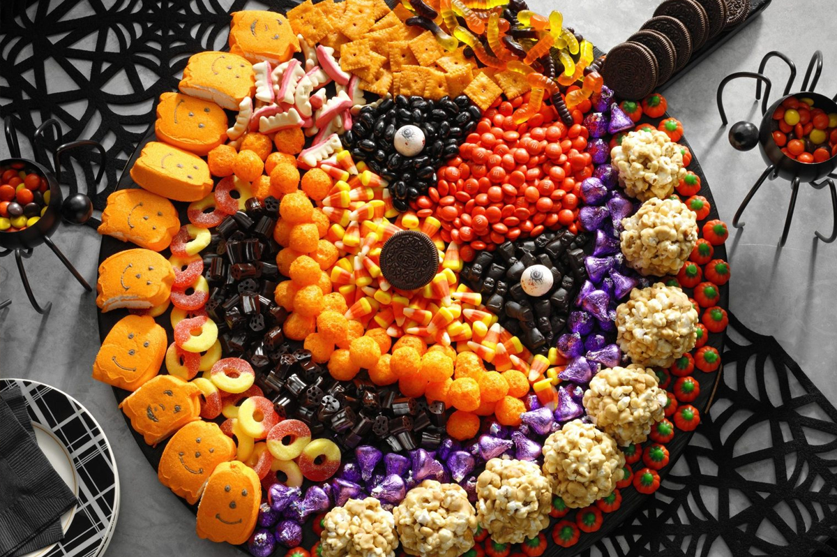 Taste of Home's Jack o'lantern charcuterie board is filled with candy, cheese puffs, and cheese-its.