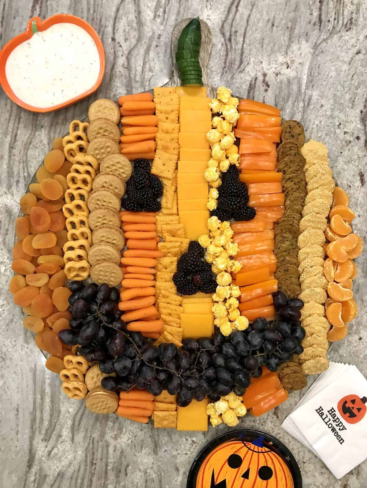 An edible pumpkin with blackberries, crackers, cookies, pretzels, and cheese fills The BakerMama's Pumpkin Board.