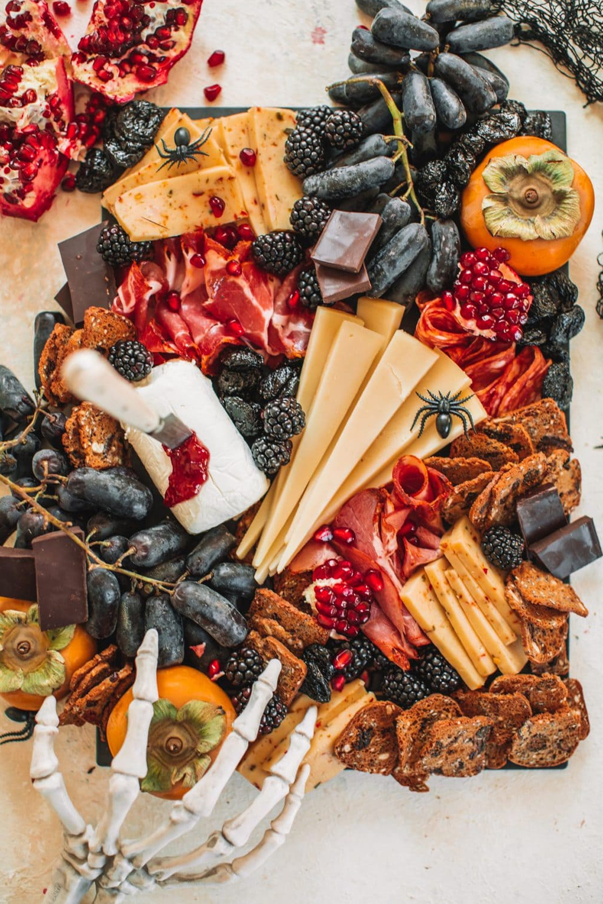 The College Housewife's Halloween Board presents grapes, crackers, meats, and cheeses.