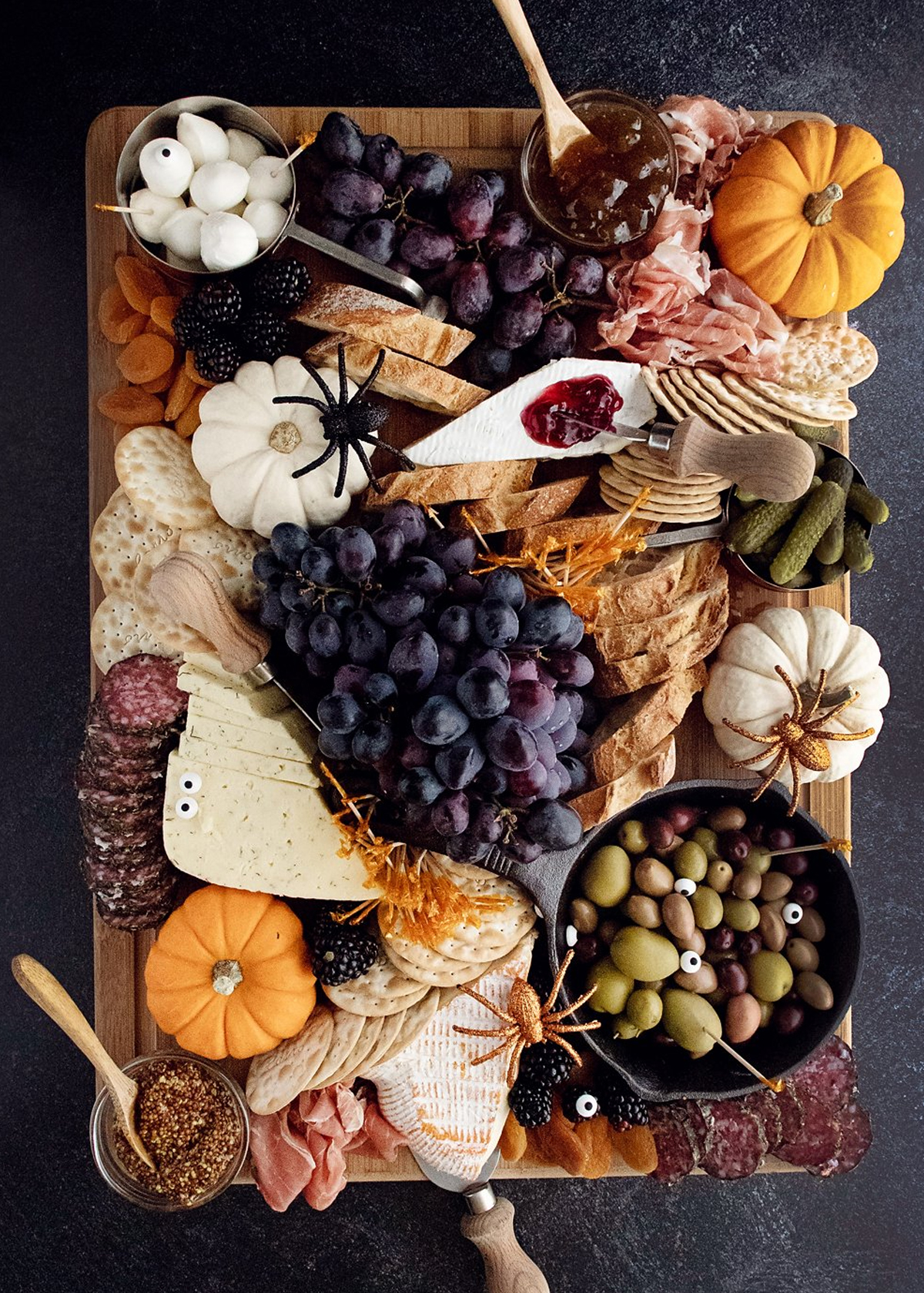 The Creative Bite's Halloween board showcases grapes, cheese, meats, and crackers.