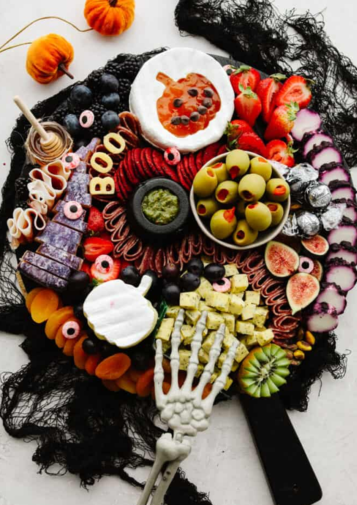 Pumpkin shaped brie with jelly, olives, cheese, meats, and fruit complete The Recipe Critic's Halloween Charcuterie Board.