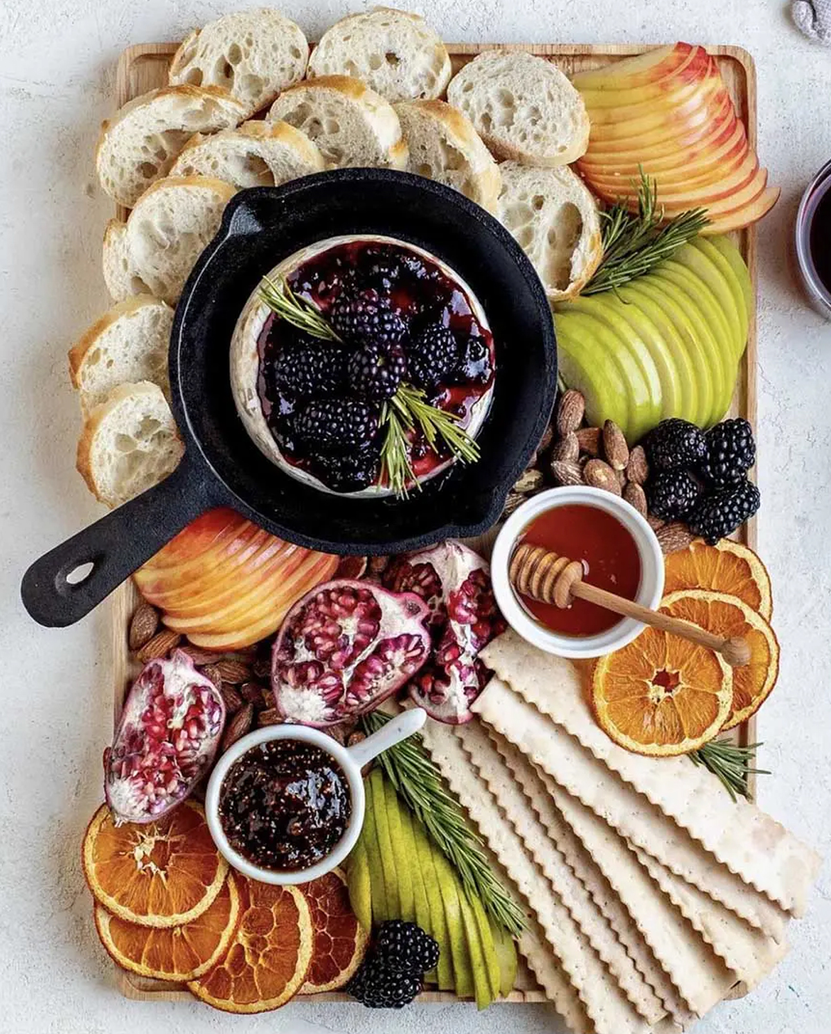 Ain't Too Proud to Meg's board displays brie,, fig jam, apples, bread, and berries.