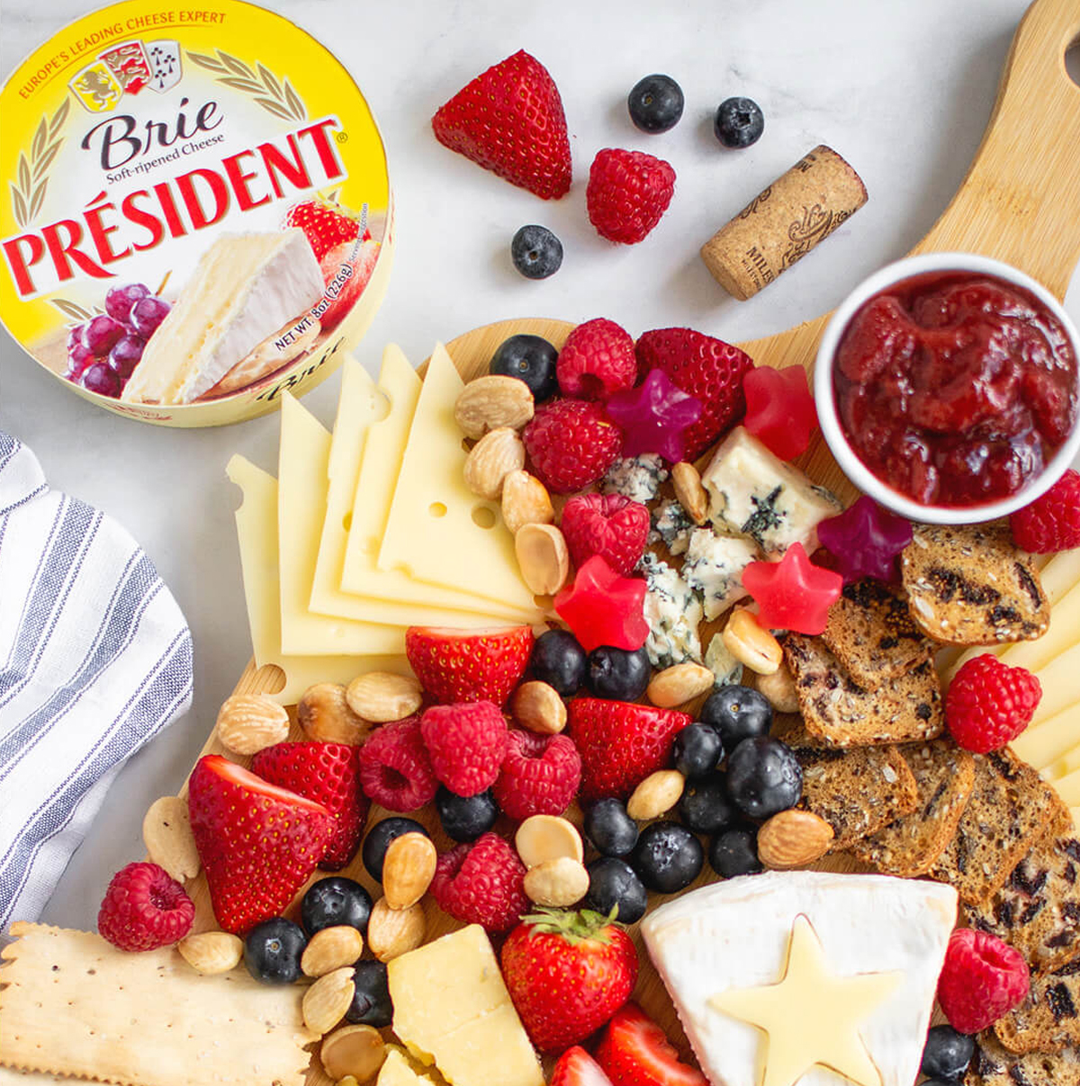 Brie cheese, jelly, berries, and crackers are included on President Cheese's Brie board.