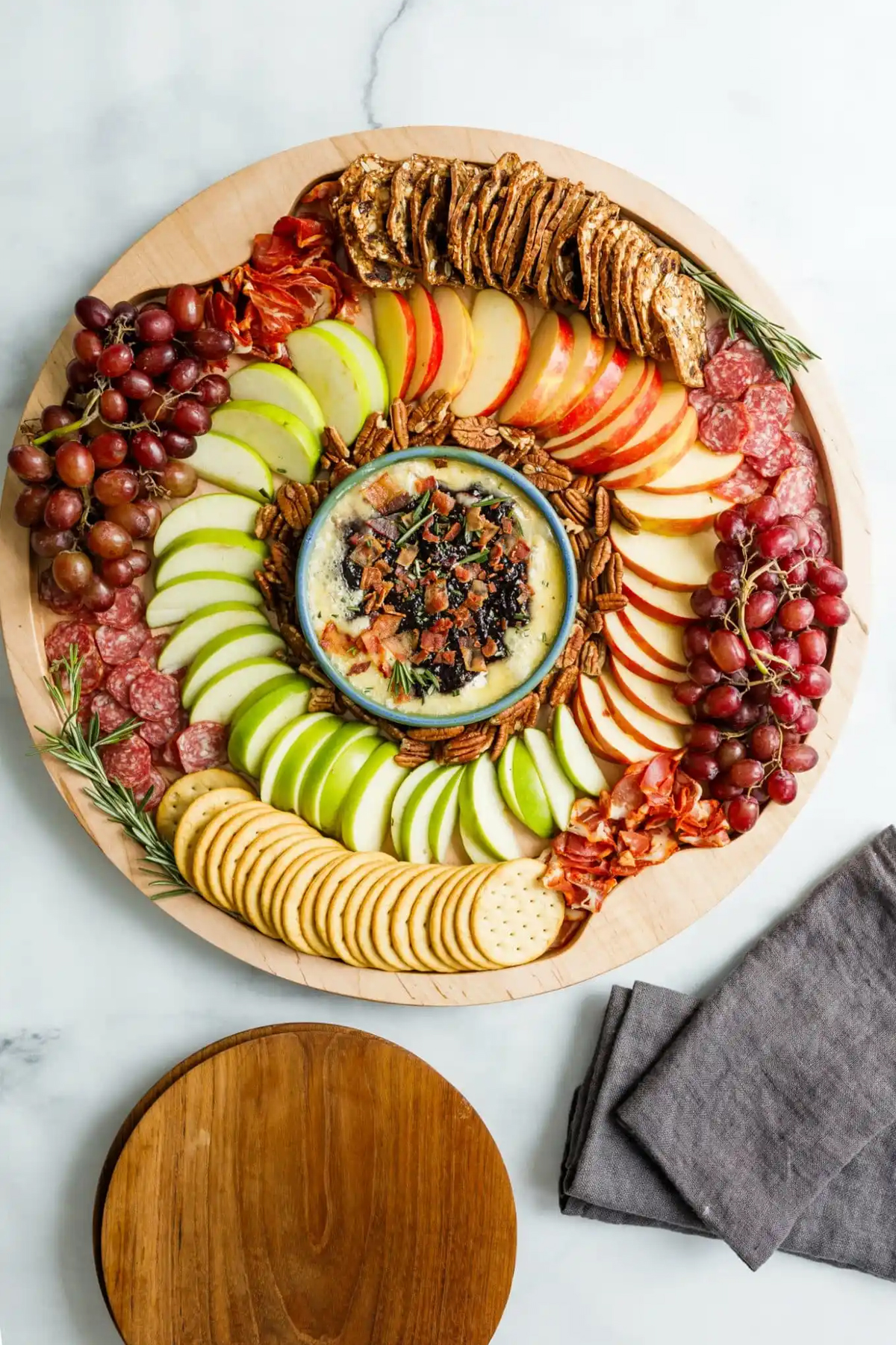 The Reluctant Entertainer has included a wheel of brie, meats, crackers, apples, and nuts on their brie board.