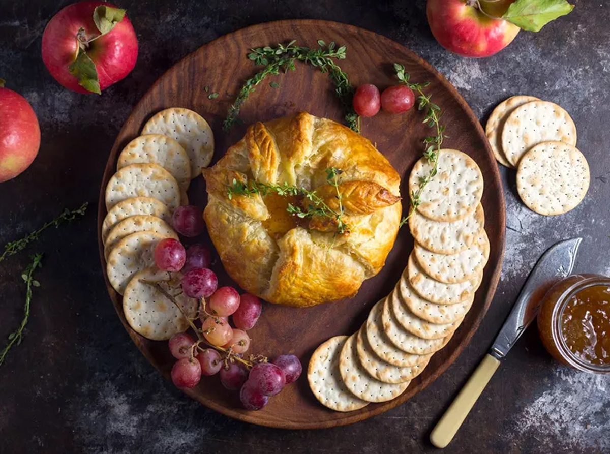Serious Eats shows a baked brie ball wrapped in bread with seasonal fruit and cheese.