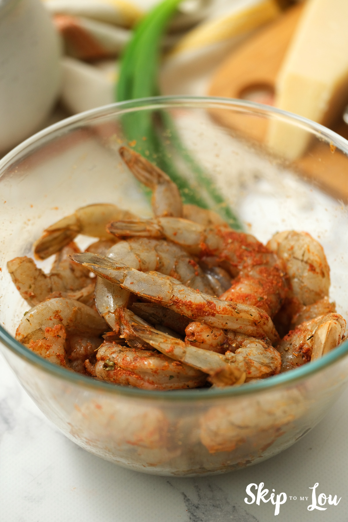 Raw shrimp with Cajun seasoning in a glass bowl, by Skip to my Lou.