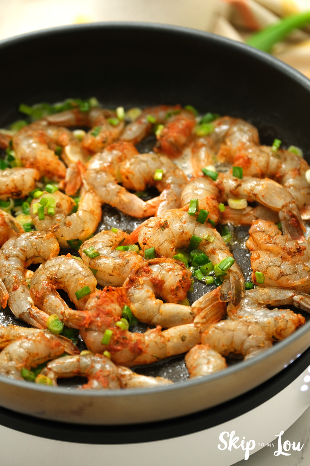 Cajun seasoned shrimp, melted butter and green onions in a large skillet, by Skip to my Lou.