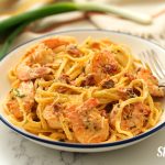 Creamy Cajun shrimp pasta served with a fork in a bowl, by Skip to my Lou.
