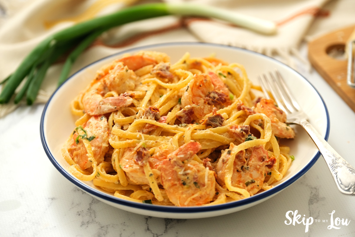 Creamy Cajun shrimp pasta served with a fork in a bowl, by Skip to my Lou.