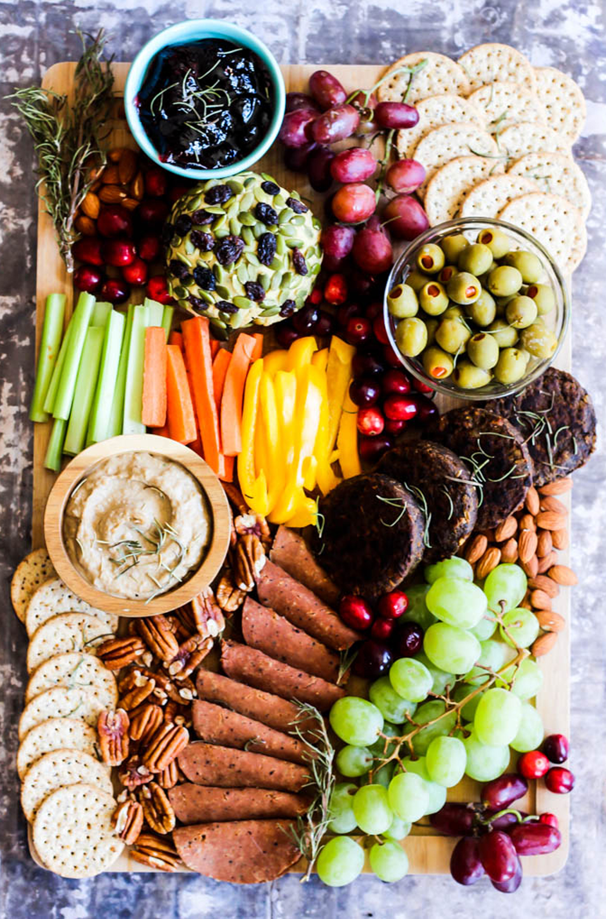 Jelly, grapes, nuts, crackers, celery, carrots, and olives are included on Emilie Eats charcuterie board.