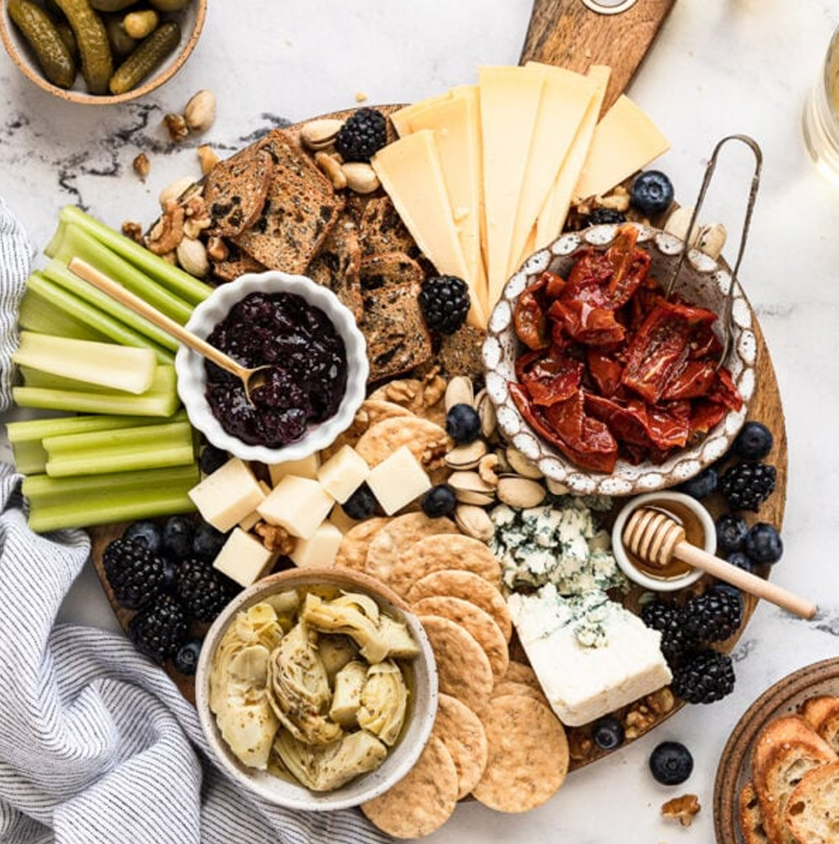 Fork in the Kitchens board shows dill pickles, cheeses, roasted tomatoes, and berries.