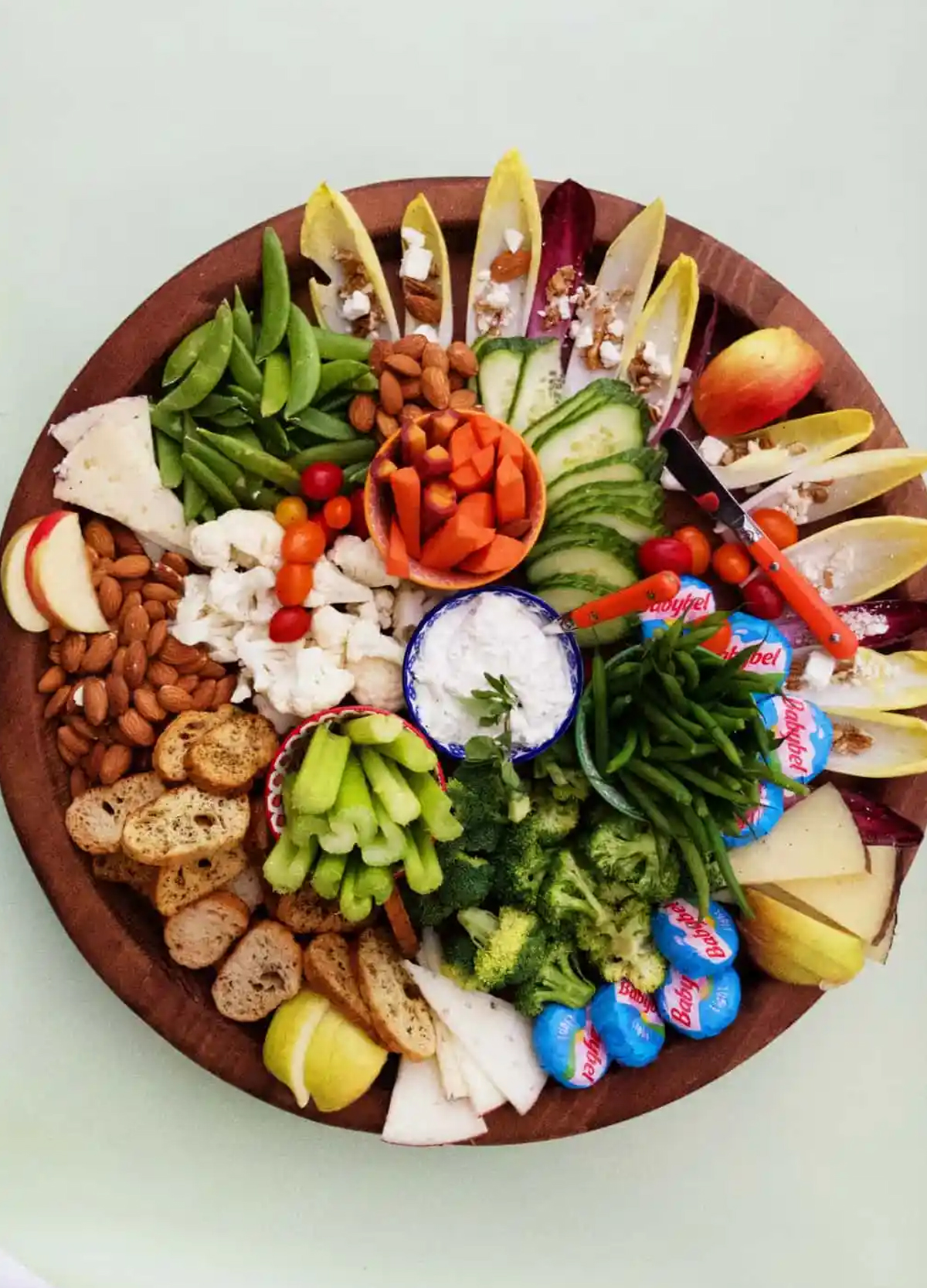 Celery, cucumbers, broccoli, nuts, and cheese are shows on Reluctant Entertainers cheese board.